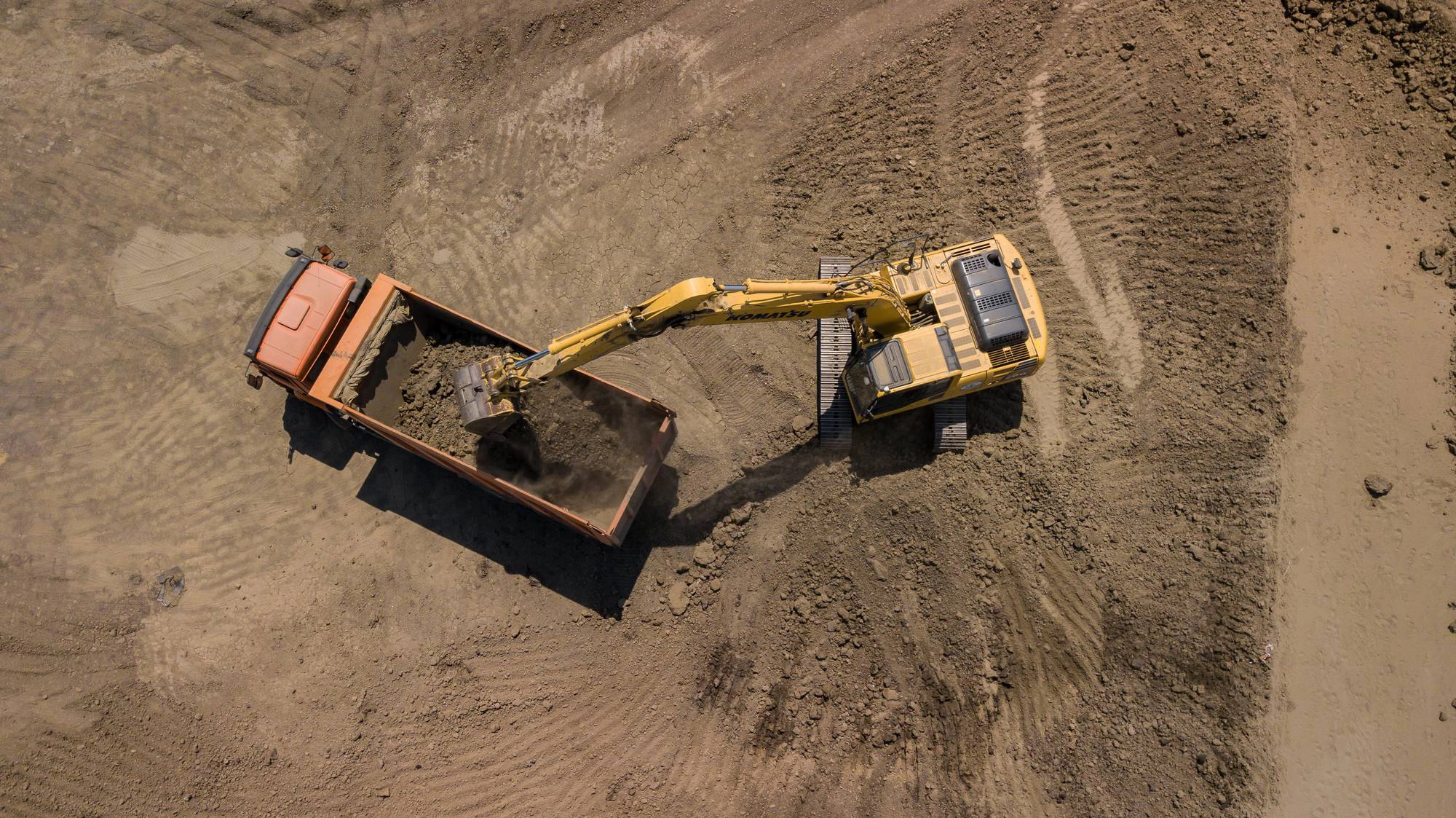 An autonomous mining truck operating in a large open-pit mine, with GPS and sensor systems visible on the vehicle